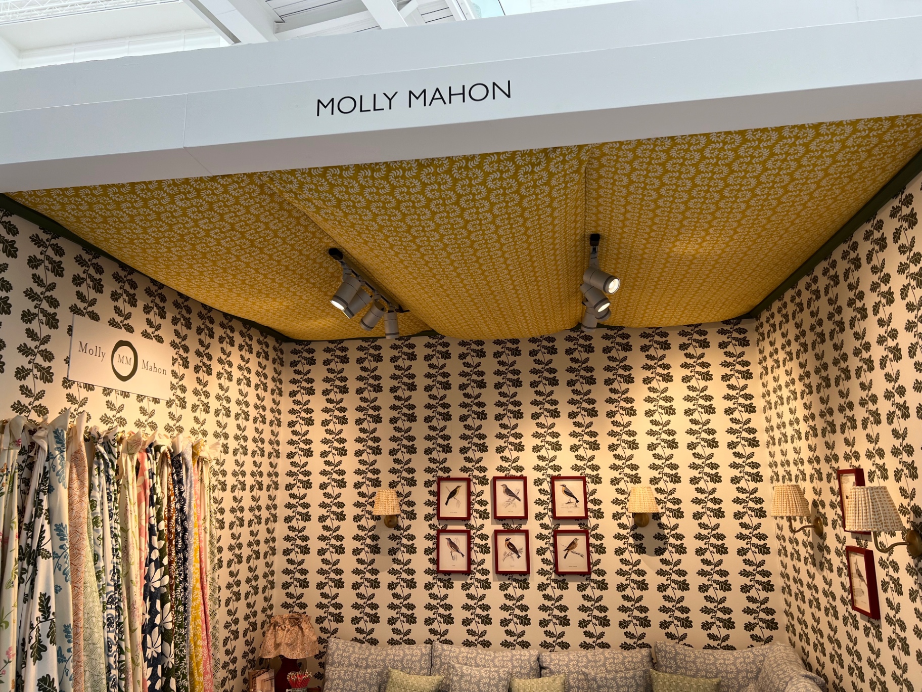 Finished Molly Mahon stand at the Chelsea Design Centre with mustard patterned ceiling canopy and oak-leaf wallpaper