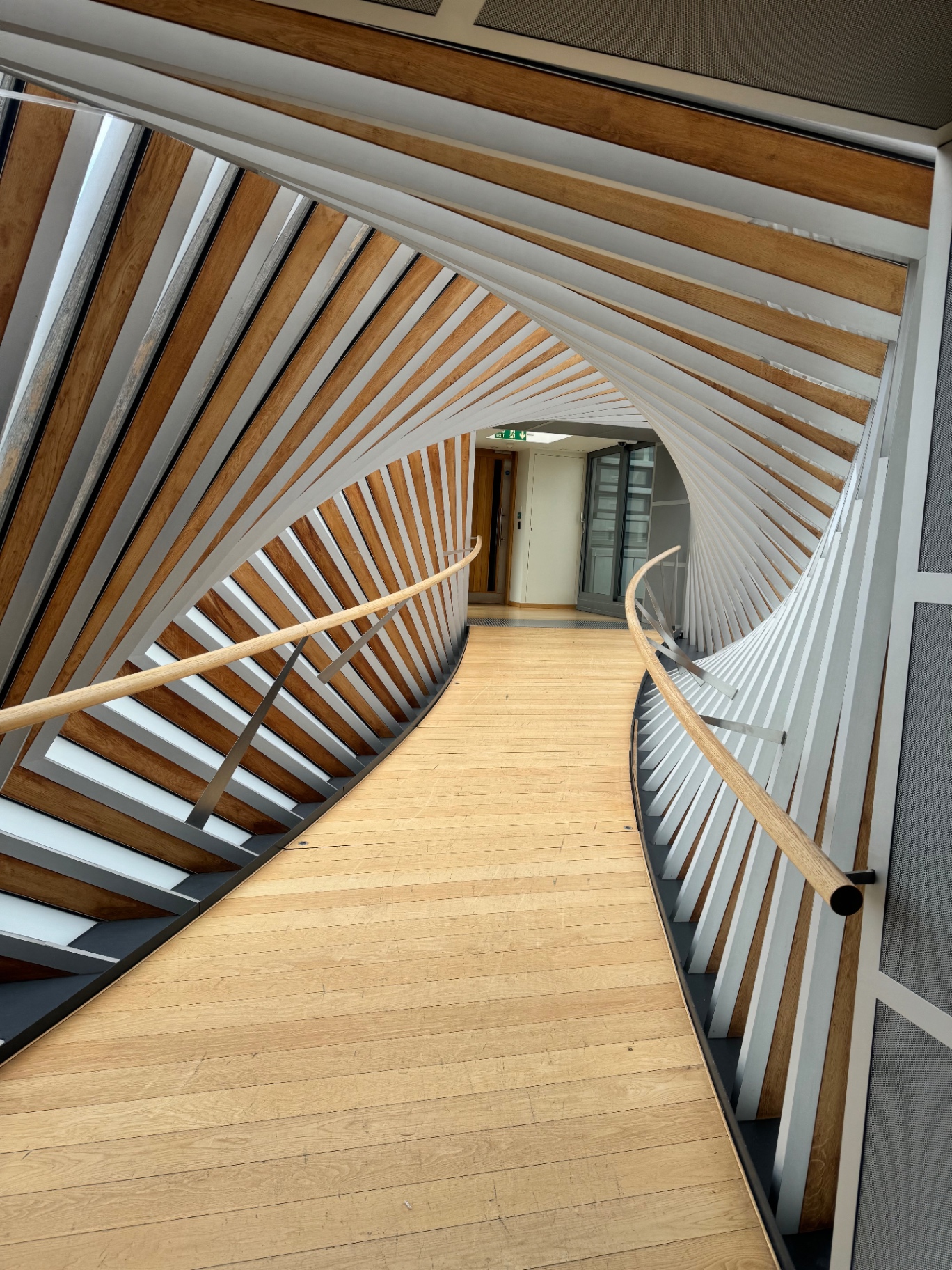 Sculptural timber-and-steel spiral staircase inside a contemporary London venue
