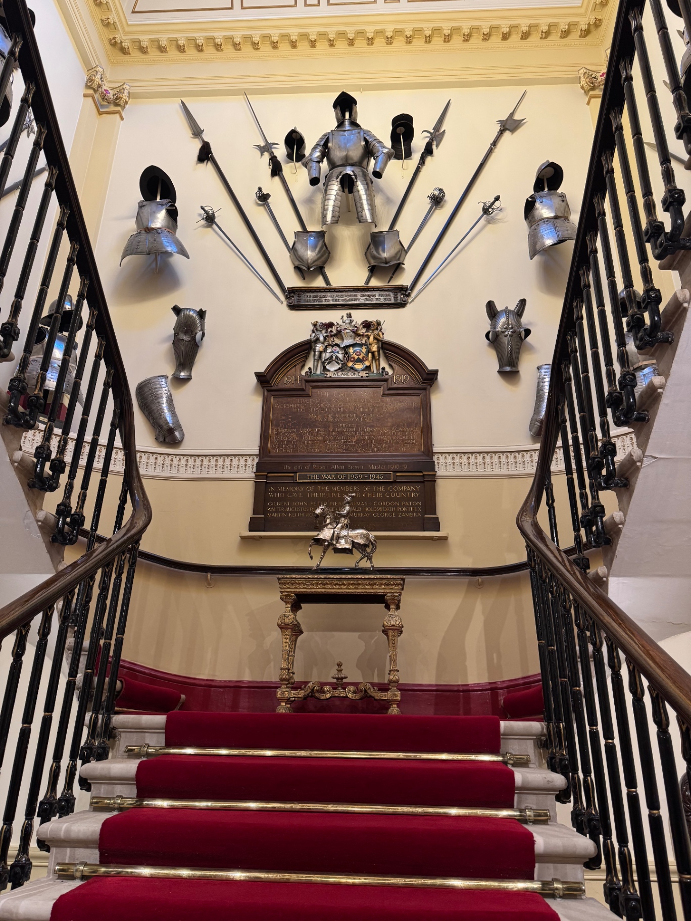 Grand staircase with red carpet runner and historic armour display at a private London venue