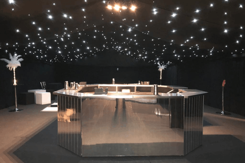 Circular mirrored bar under a starlit black marquee ceiling with feather centrepieces