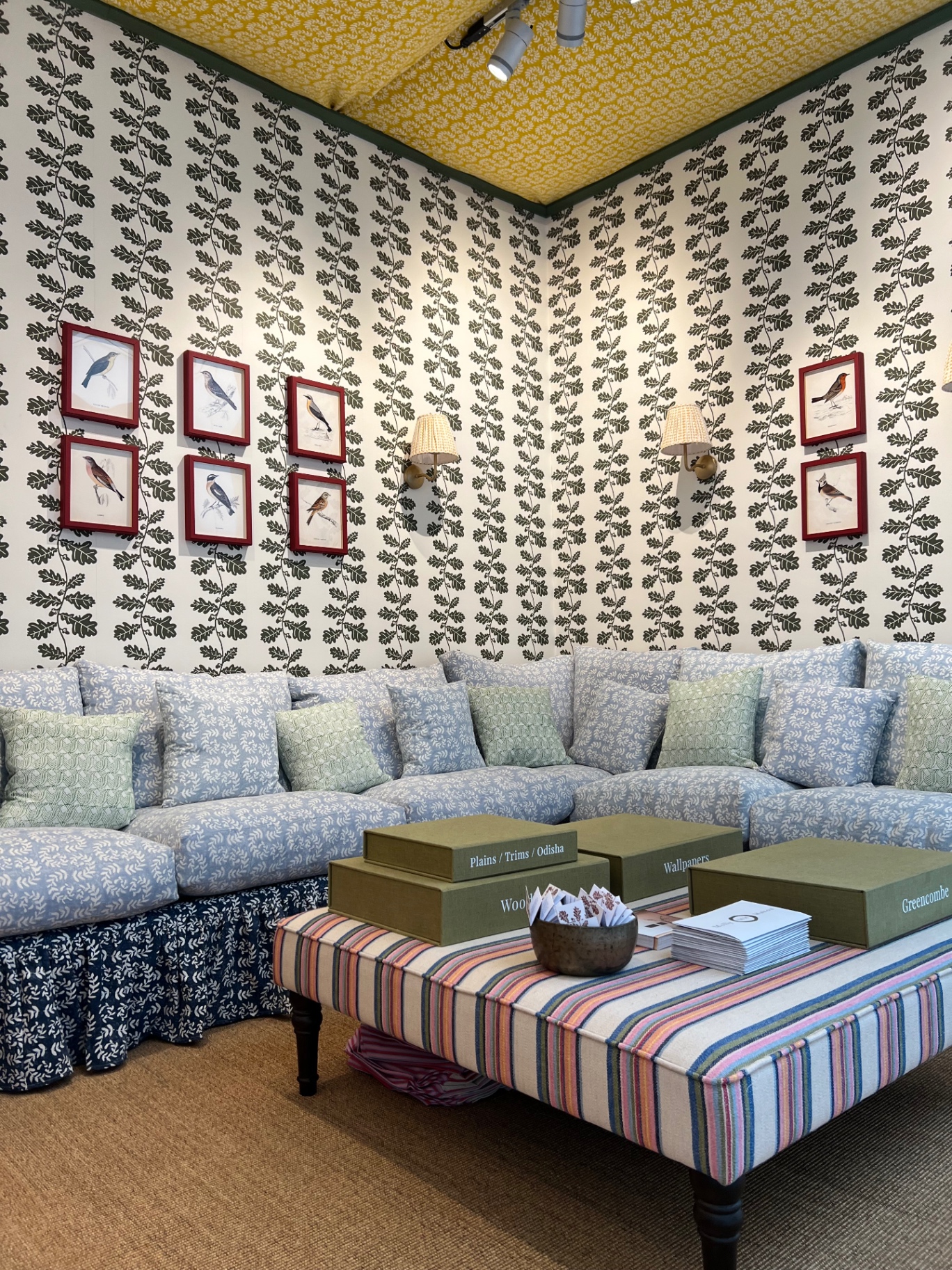 Patterned sofa detail with sample books arranged on a striped ottoman on the finished stand