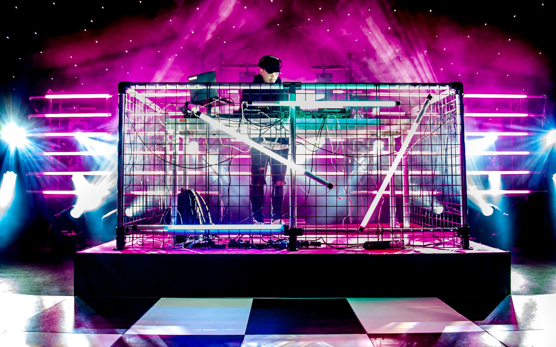 DJ performing under vibrant pink and blue stage lights at a private celebration
